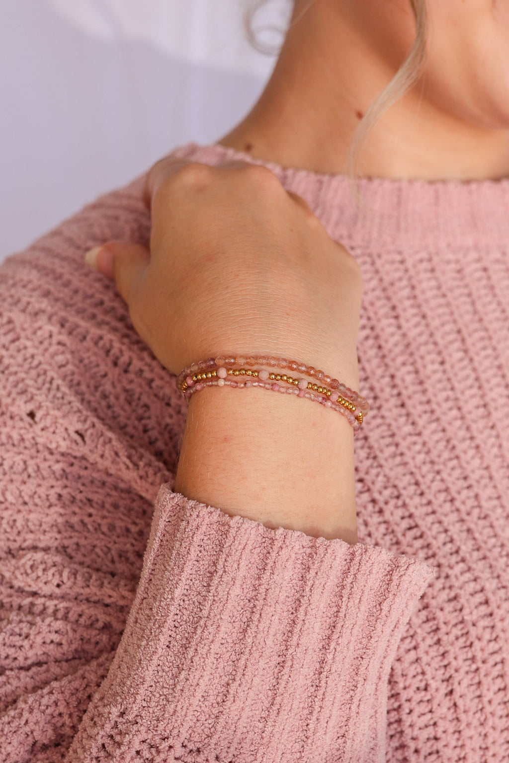Wrist-worn bead stretch bracelet set with pink beads, gold beads, and stacked bands