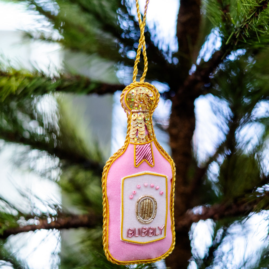 Pink champagne bottle ornament with gold sequined neck, ribbon bow, and 'CUBBY' label