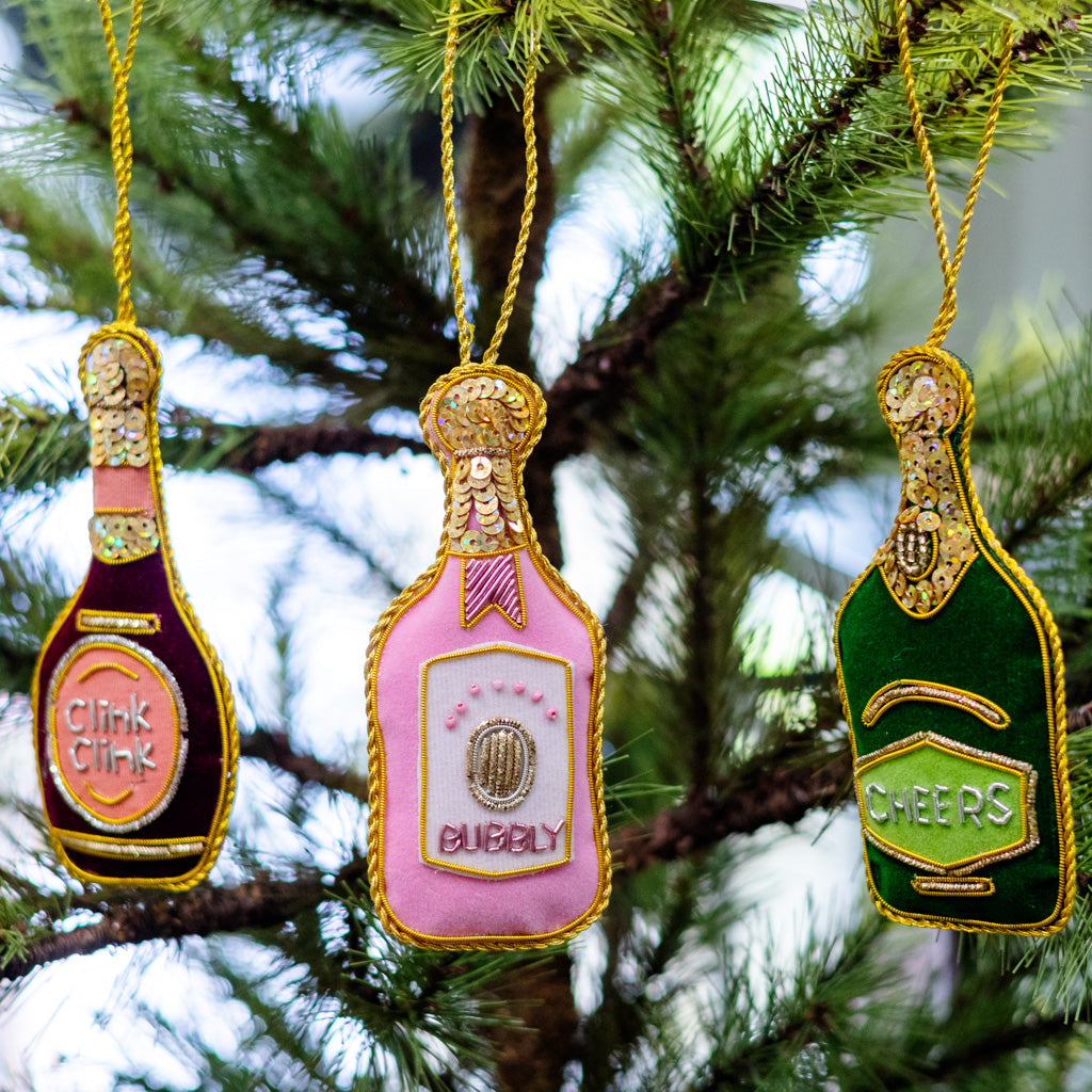 Three bottle ornaments on string: pink 'CUBBY', green 'CHEERS', dark 'CLINK CLINK'