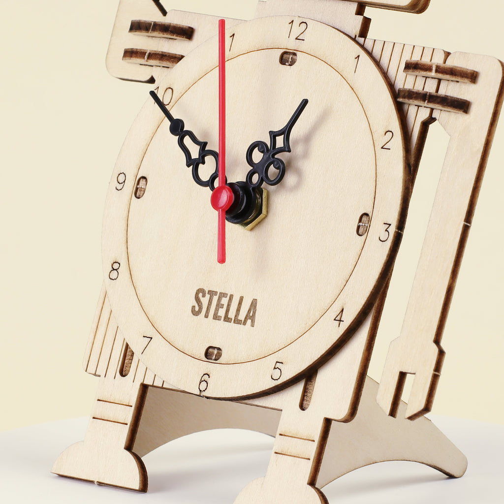 Wooden robot clock dial close-up with black hands, red second hand, and “STELLA” text