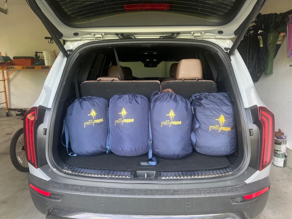 Folded outdoor blanket set in light blue, stored in a car trunk.