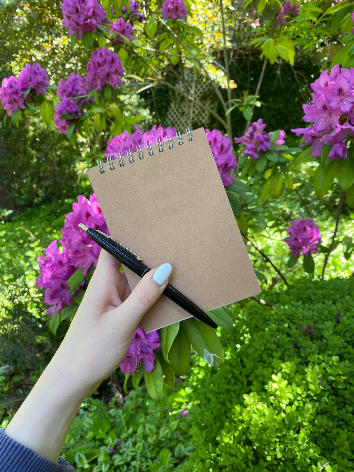 Medium kraft spiral-top notebook held in hand, wire binding visible