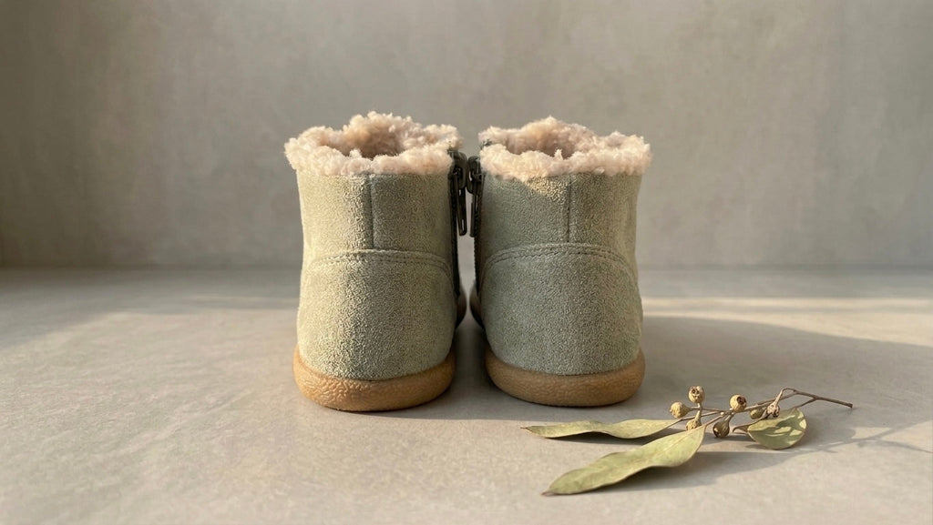 Back view of beige/tan toddler winter barefoot boots with rear zipper and sherpa trim
