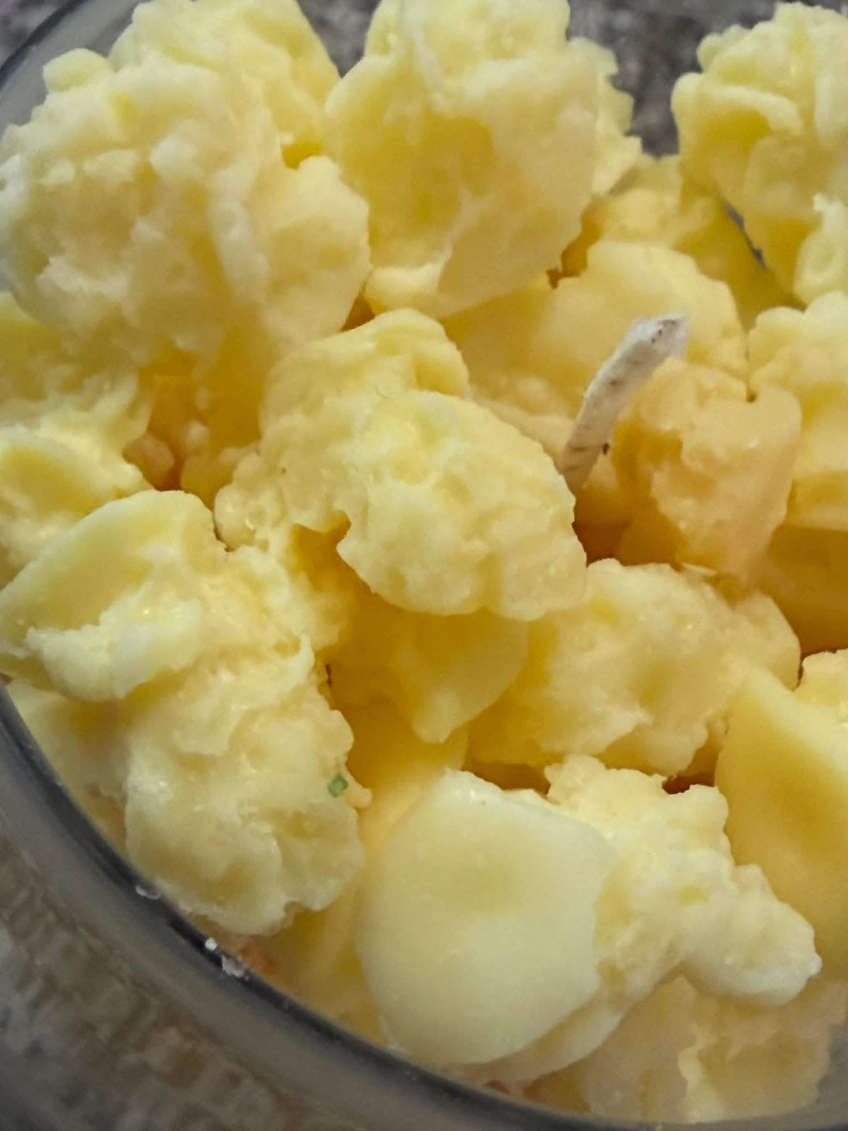 Close-up of yellow popcorn-style wax chunks in a glass candle holder