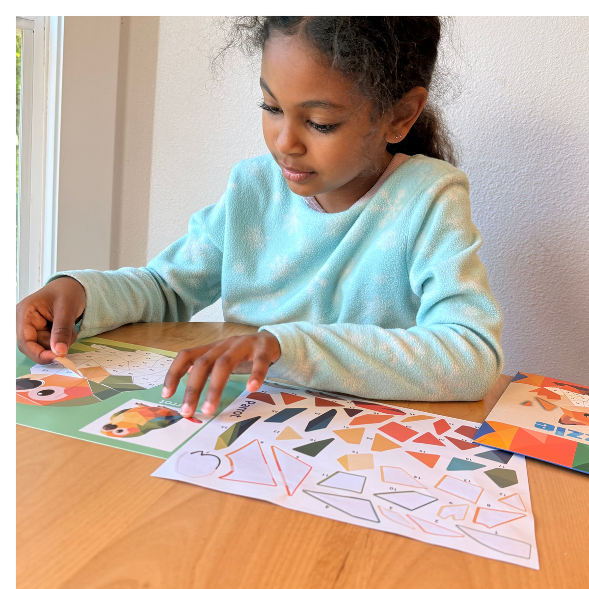 Child using sticker puzzle painting sheets on a table with colorful animal sticker pieces