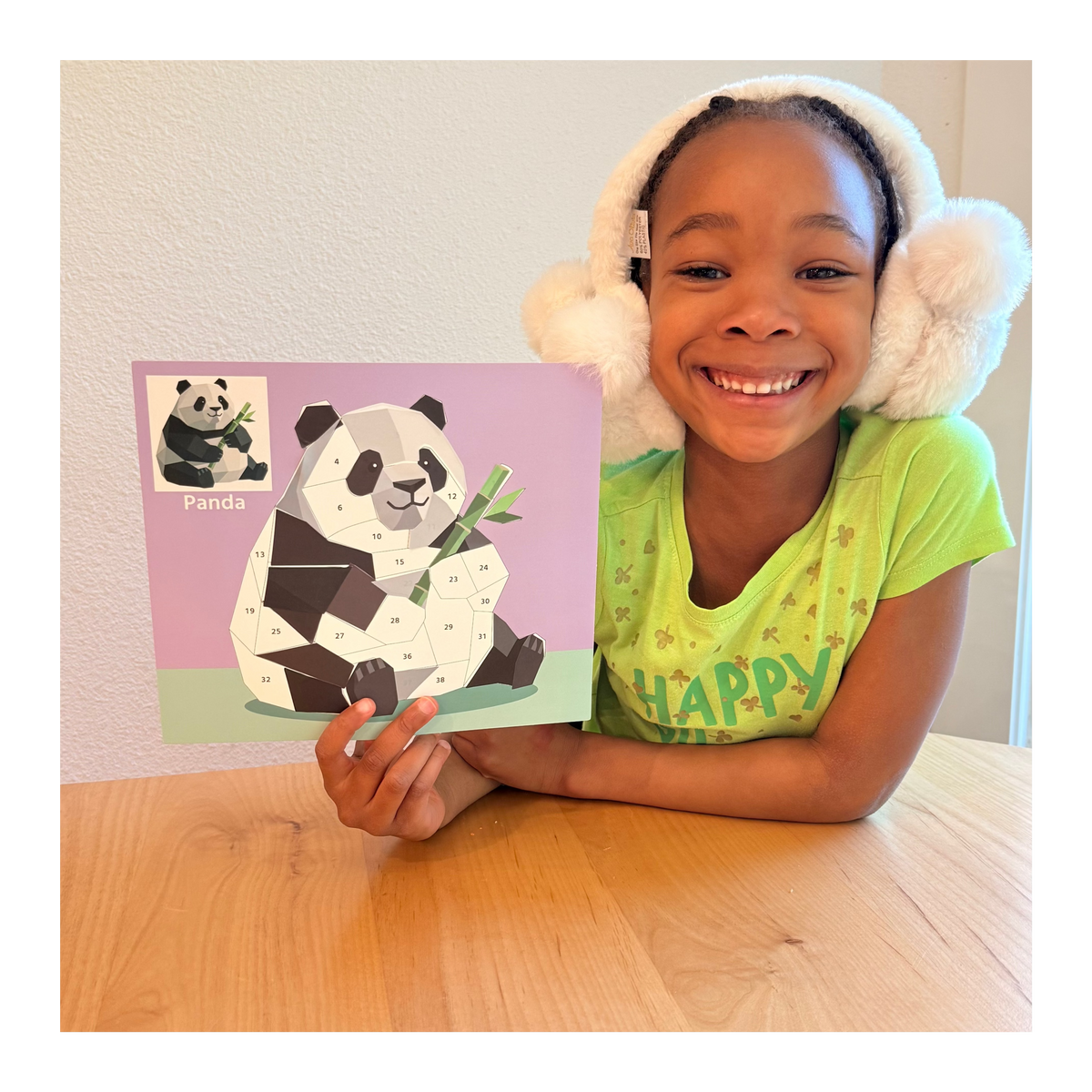 Child holding animal sticker puzzle painting kit with numbered panda pieces