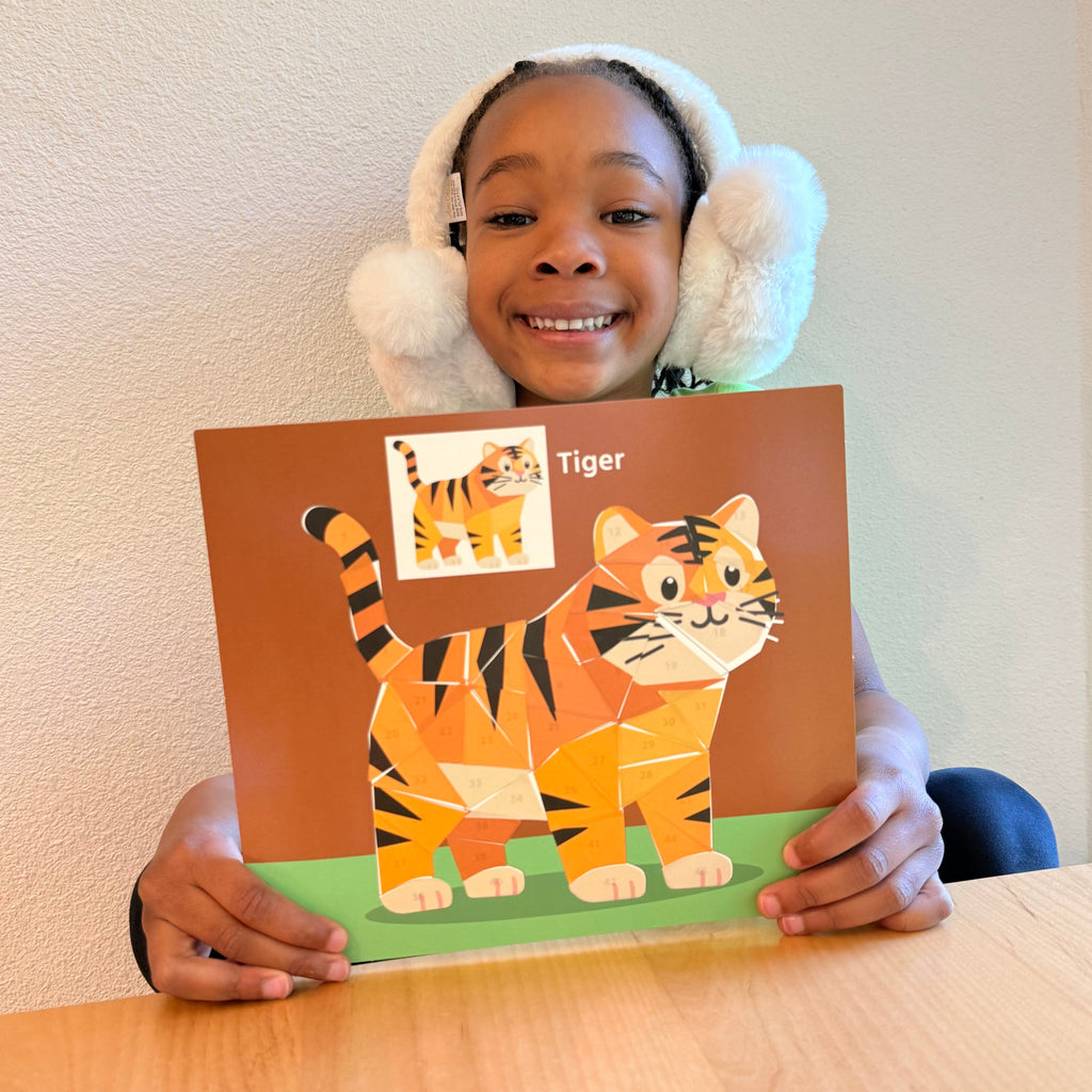 Child holding animal sticker puzzle painting kit with numbered tiger pieces and sample