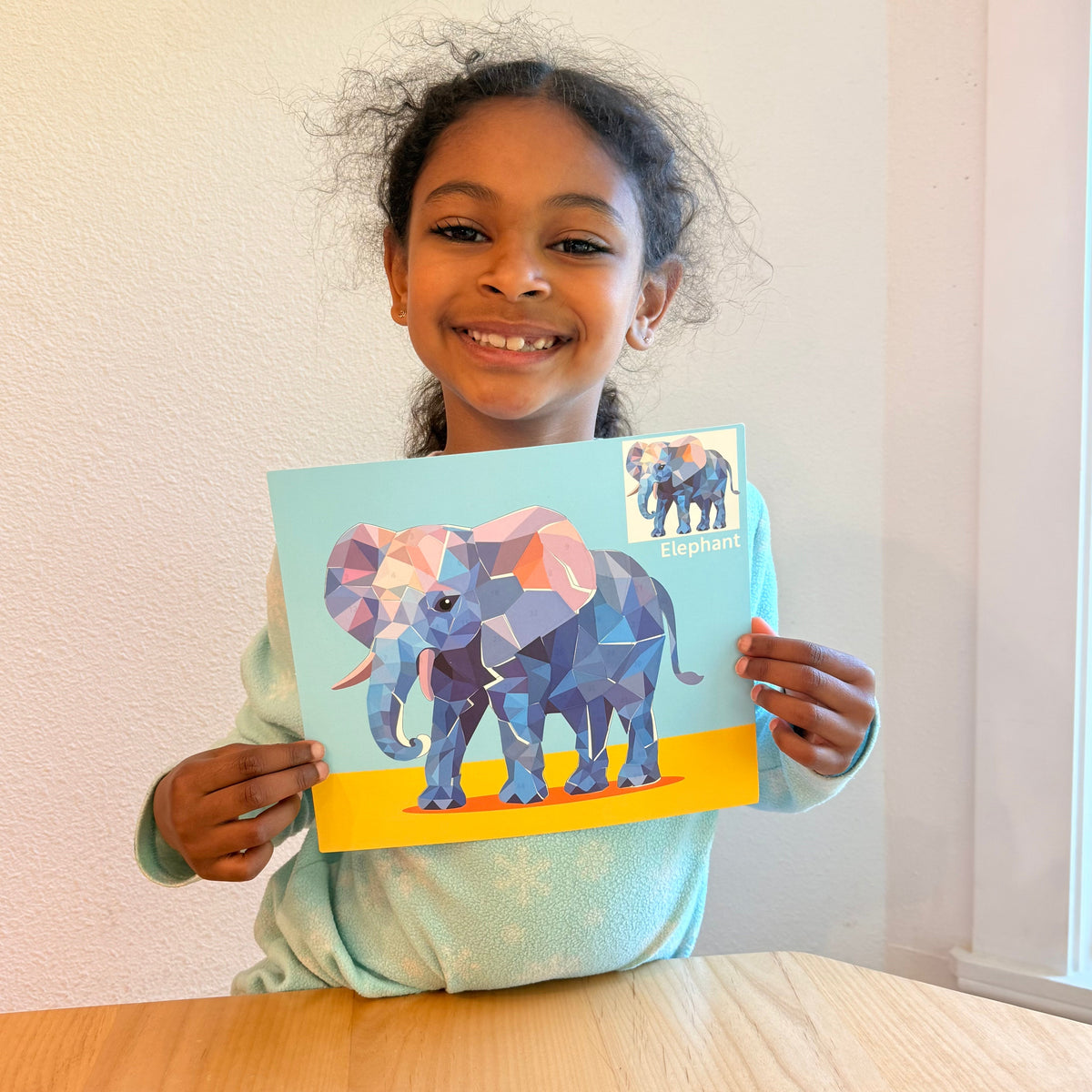 Kids sticker puzzle painting sheet with large elephant design, held by a child