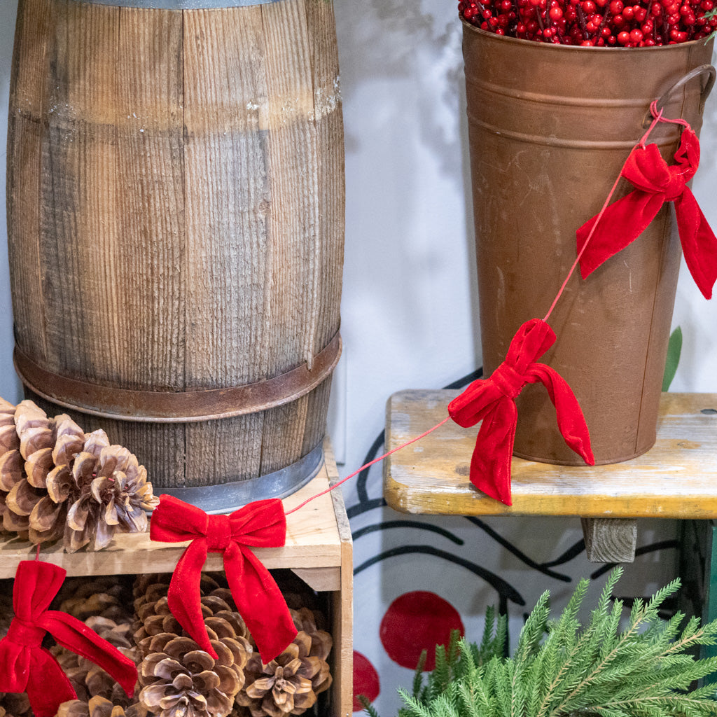 Red velvet bow garland draped on a brown bucket with bow knots