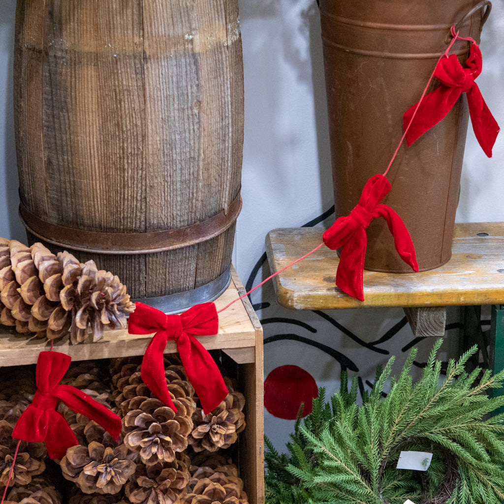 Red velvet bow garland on brown bucket, showing two tied bows and cords