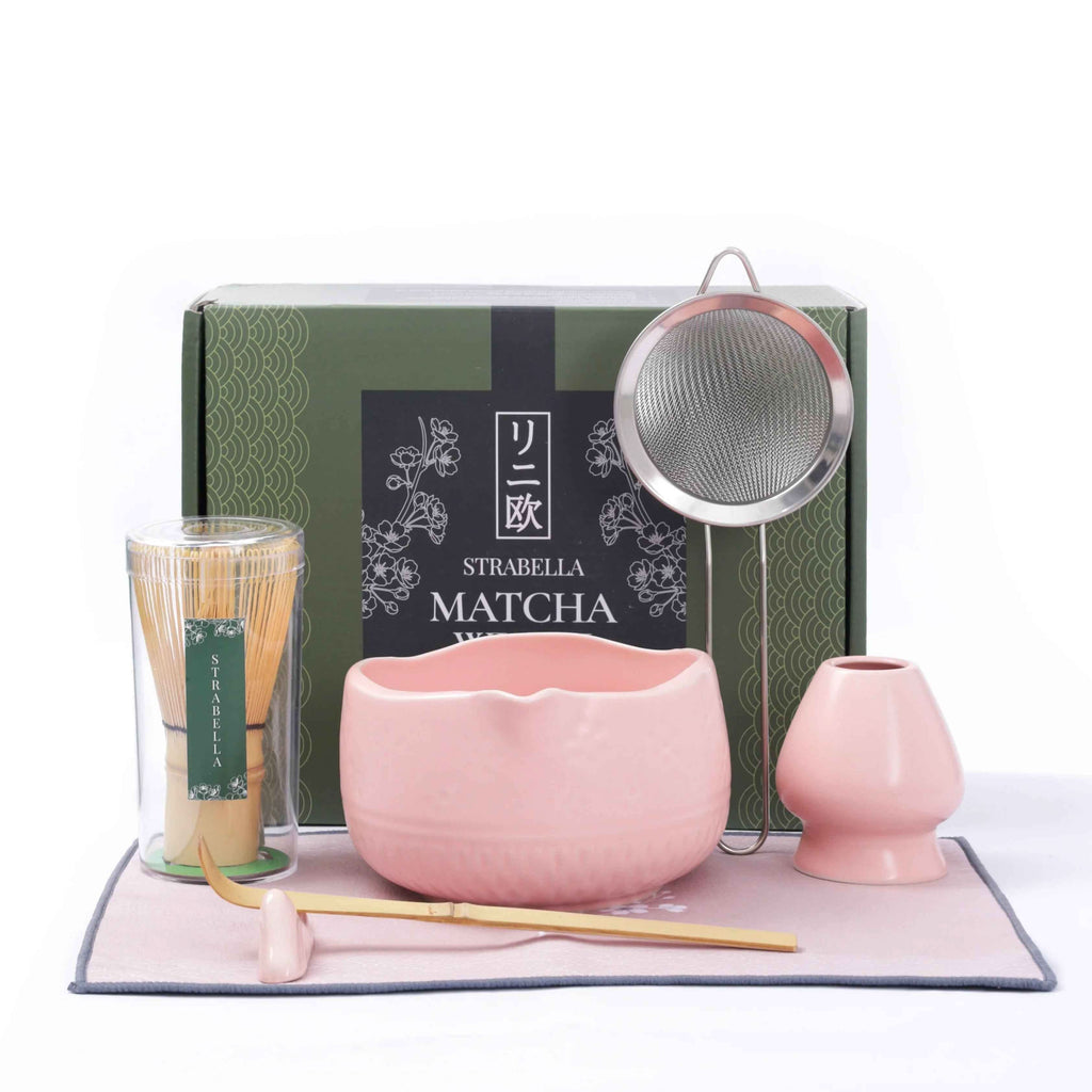 Matcha whisk set on mat with pink ceramic chawan, whisk, and two matching cups
