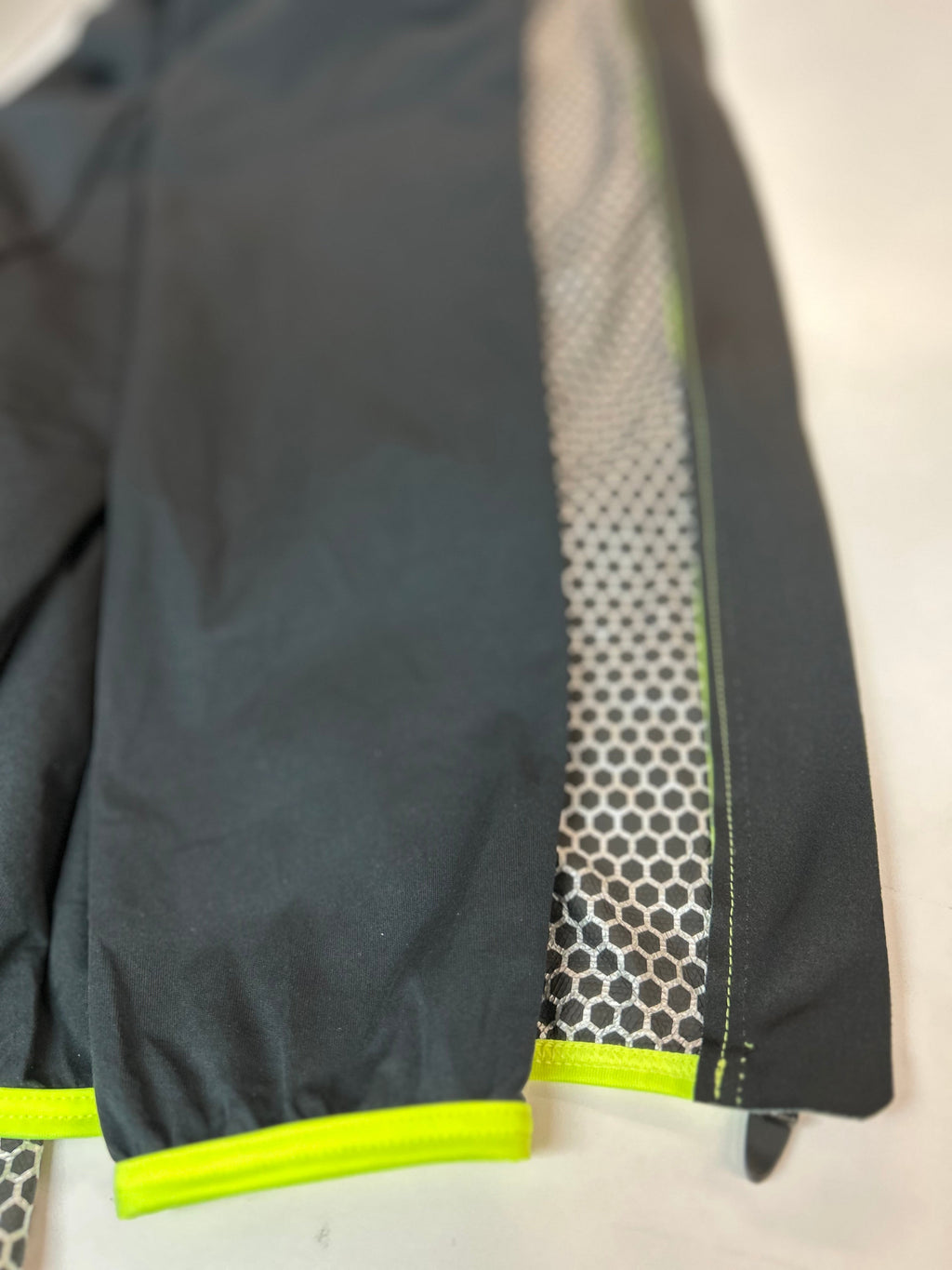 Black rain jacket sleeve close-up with neon green trim at hem