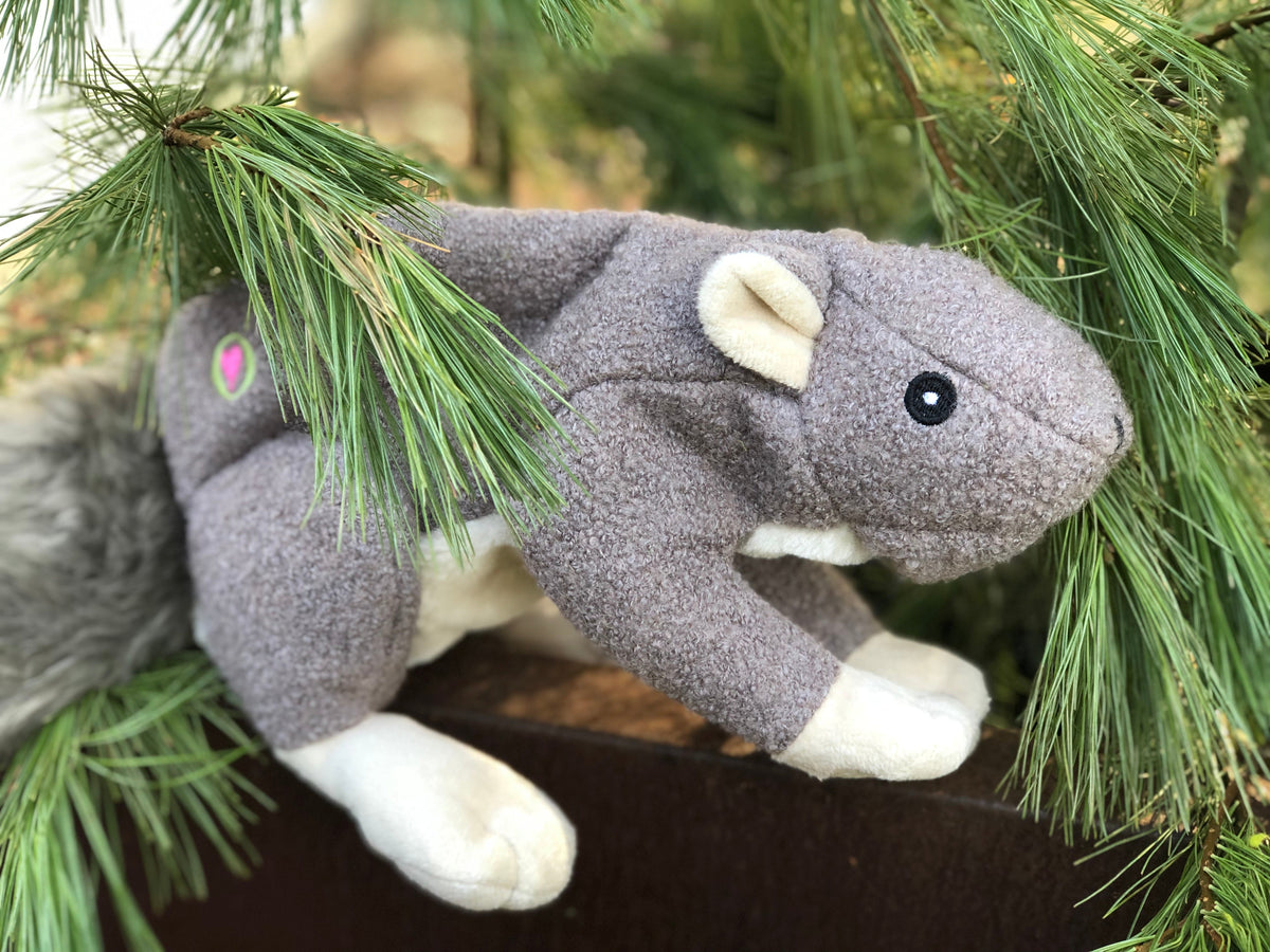 Gray plush squirrel dog toy with tan muzzle, stitched eye, and white paws