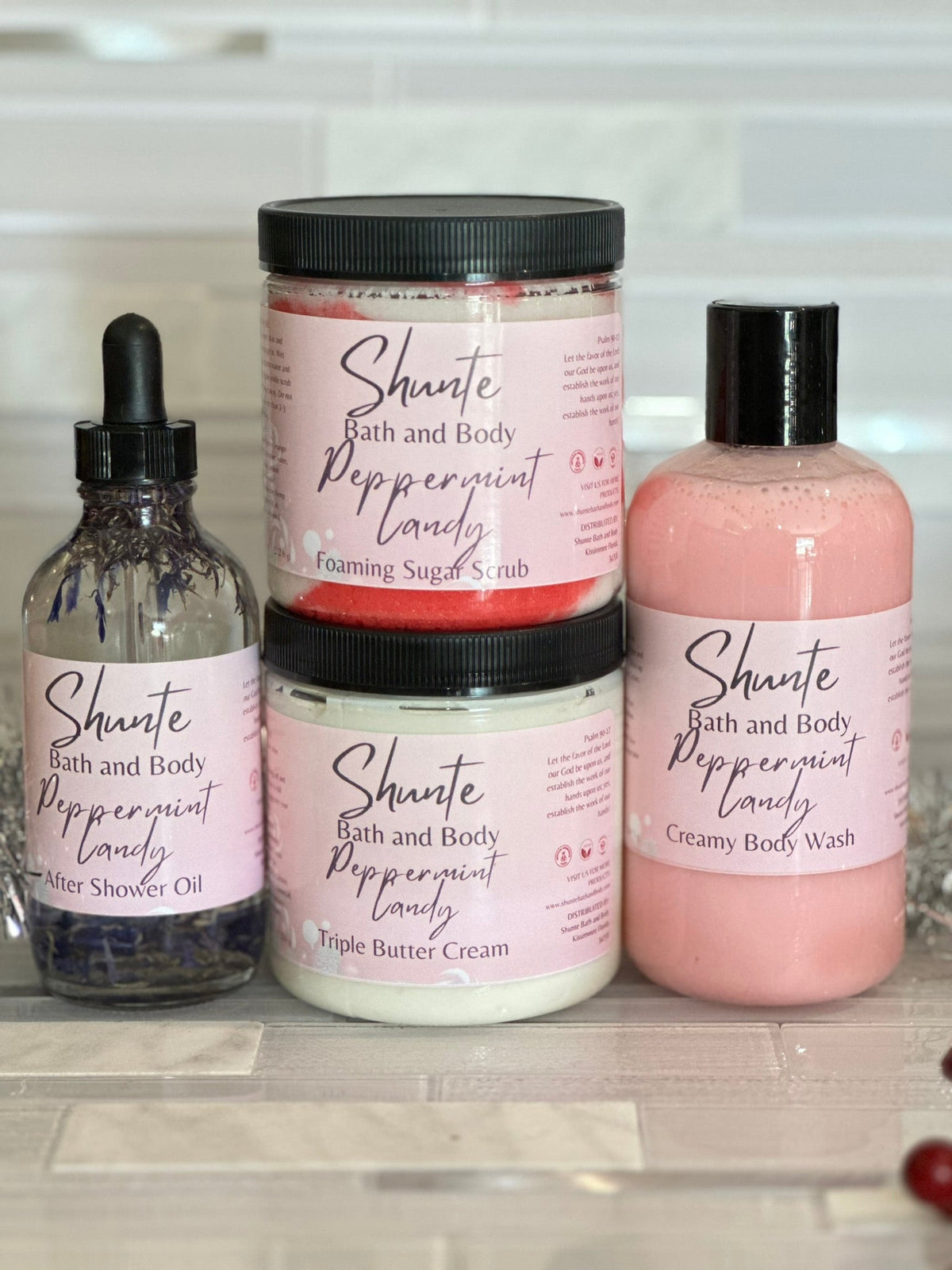 Bath and body gift set bundle with peppermint: pink scrub jar, lotion bottle, and oil bottle.