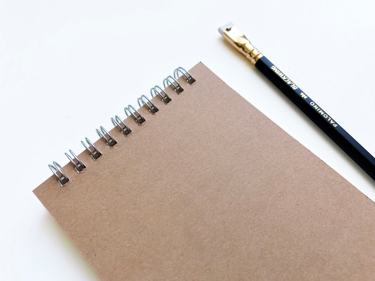 Kraft spiral notebook close-up showing metal coil binding and lined blank pages