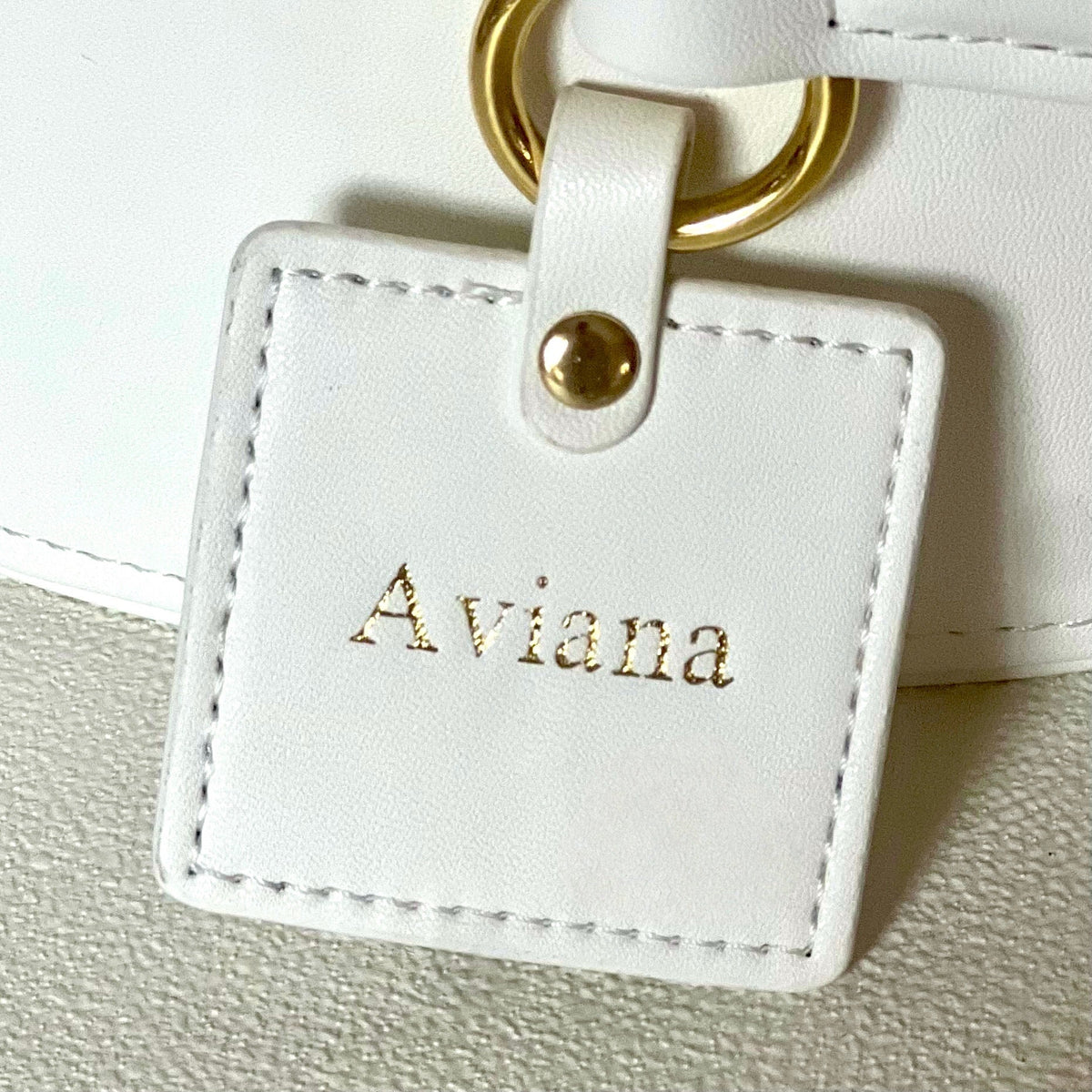 White keepsake box close-up with gold ring handle and stitched name tag “Aviana”