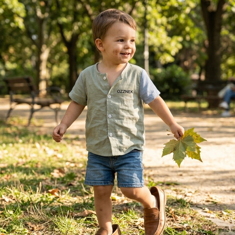 Toddler button-up shirt in sage chambray, front buttons, short sleeves on child outdoors