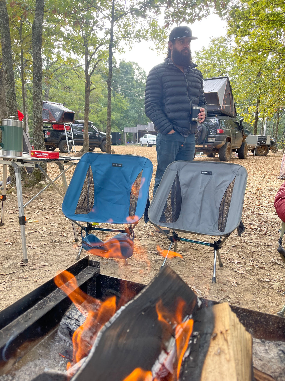 Gray camping tailgate chair with open side mesh panels by a campfire