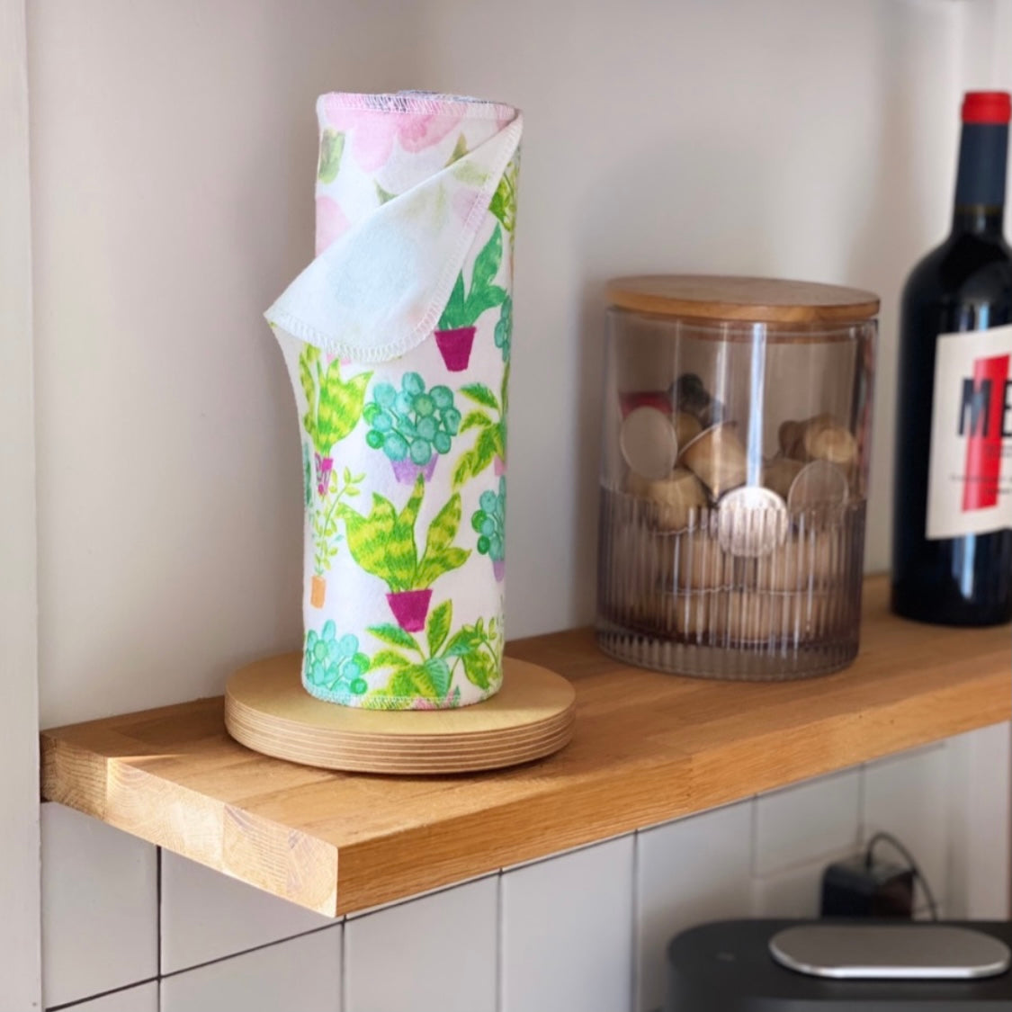 Reusable paper towel roll with green succulent and pink plant prints on wood base