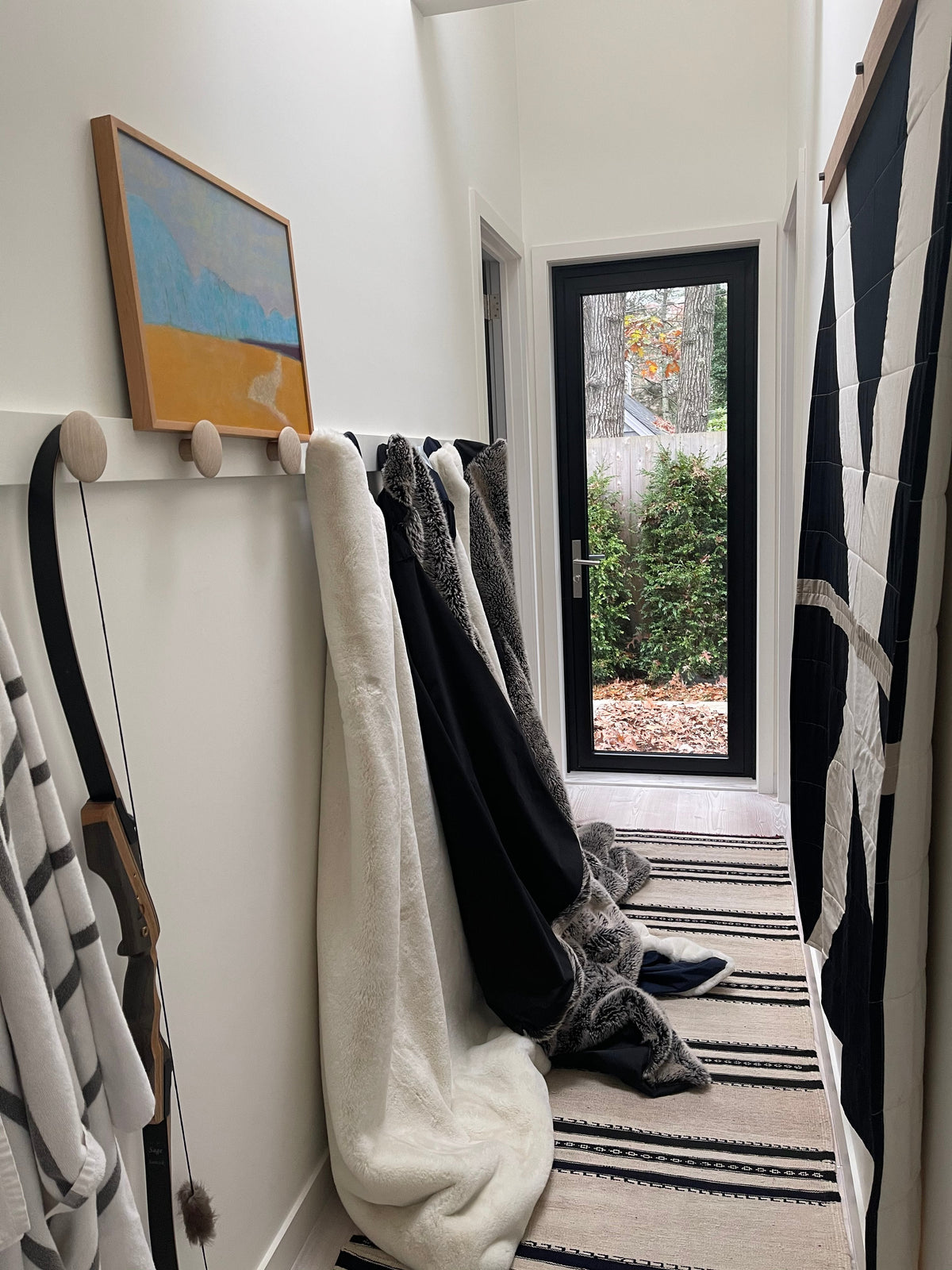 Folded outdoor blankets in black, white, and gray hanging indoors