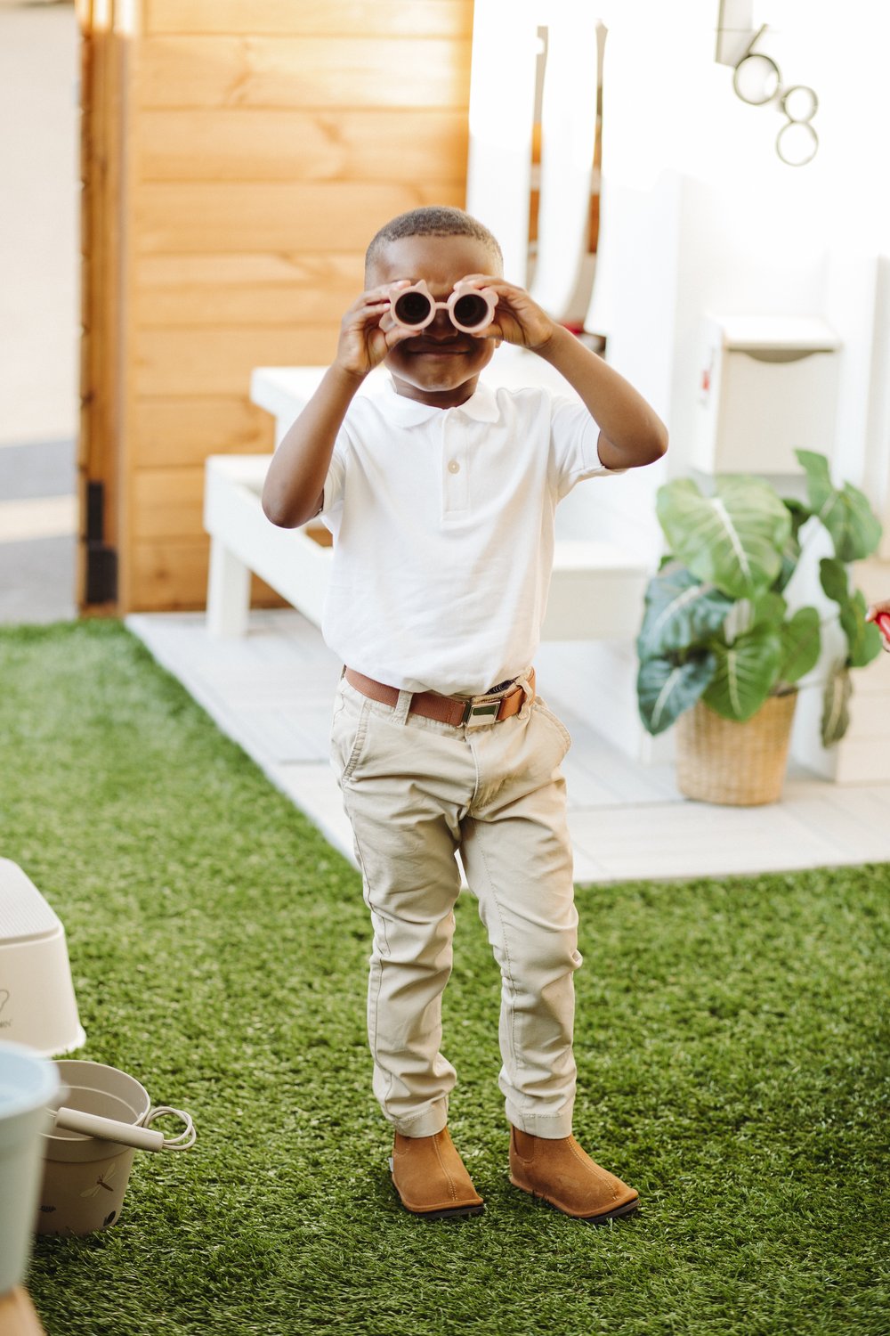 Child wearing kids brown Chelsea boots with beige pants on grass