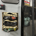 Beige-trim mesh storage pouches with zippers, stacked on a mounted panel