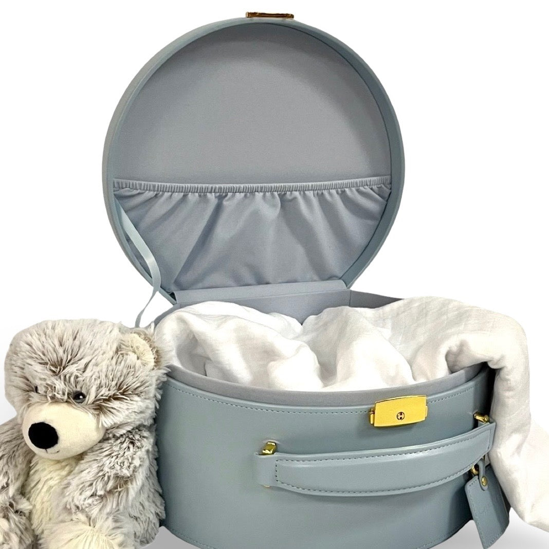 Light blue round keepsake box open with white fabric lining and plush teddy