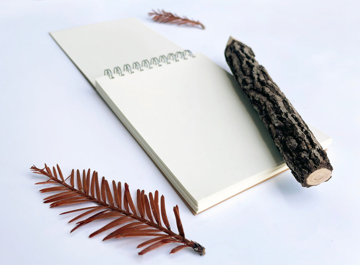 Open white spiral notebook with metal coil binding and blank page interior