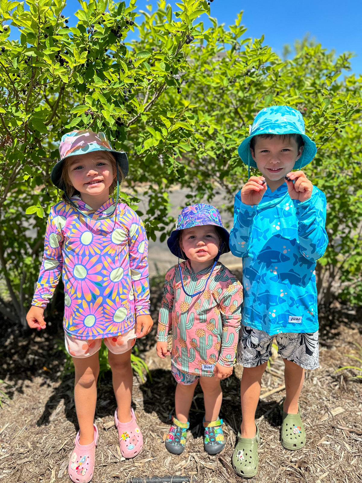 Kids sun hoodies in camo prints, including blue and pink hooded tops on children