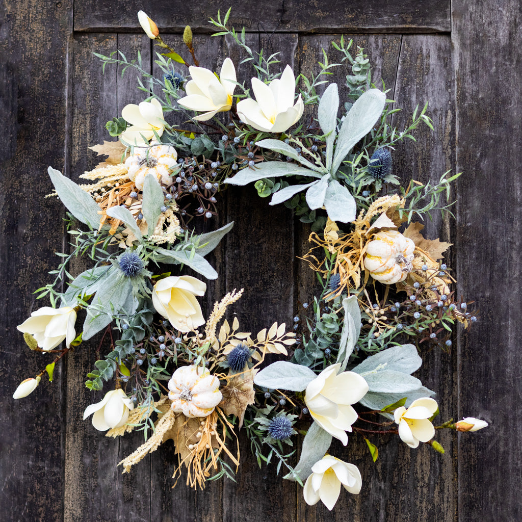 Sage wreath with white blossoms, eucalyptus leaves, blue thistle accents, and seeded stems