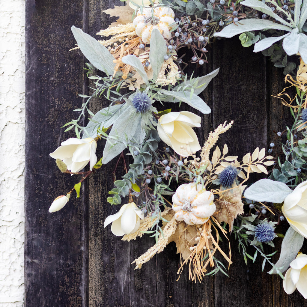 Sage wreath detail with white blossoms, silver-green leaves, blue thistle, and woven dried grass