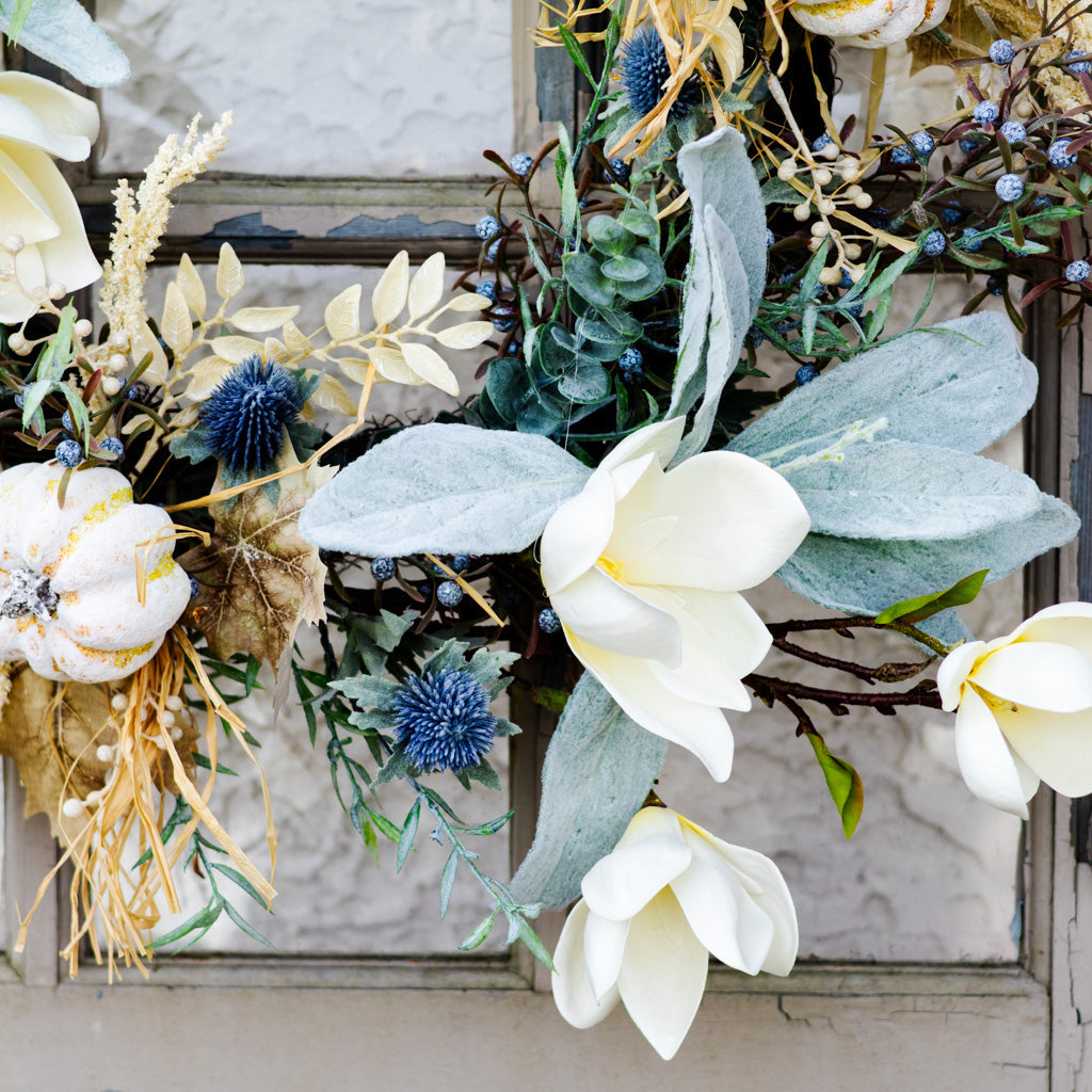 Sage wreath close-up of a large white flower with blue thistle, eucalyptus leaves, and berries