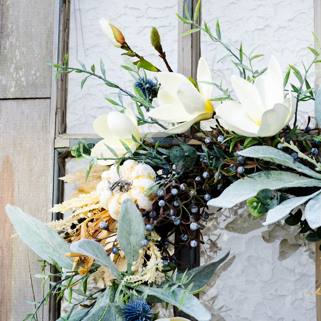Sage wreath with white flowers, green foliage, blue thistle accents, and seed-stalk garland