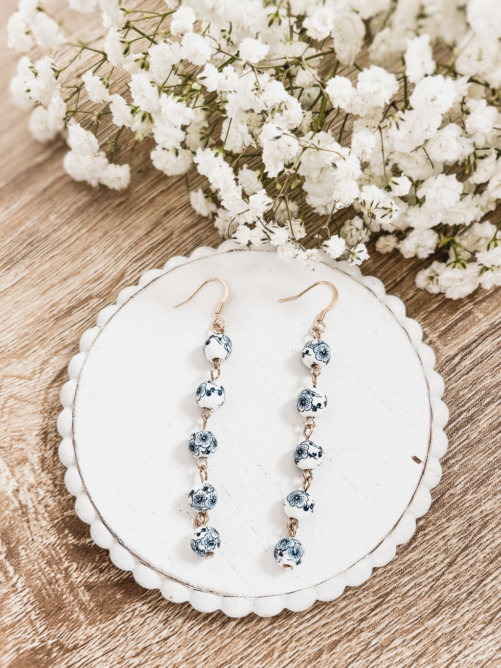 Blue porcelain bead drop earrings on white card; gold-tone hooks, five beads each