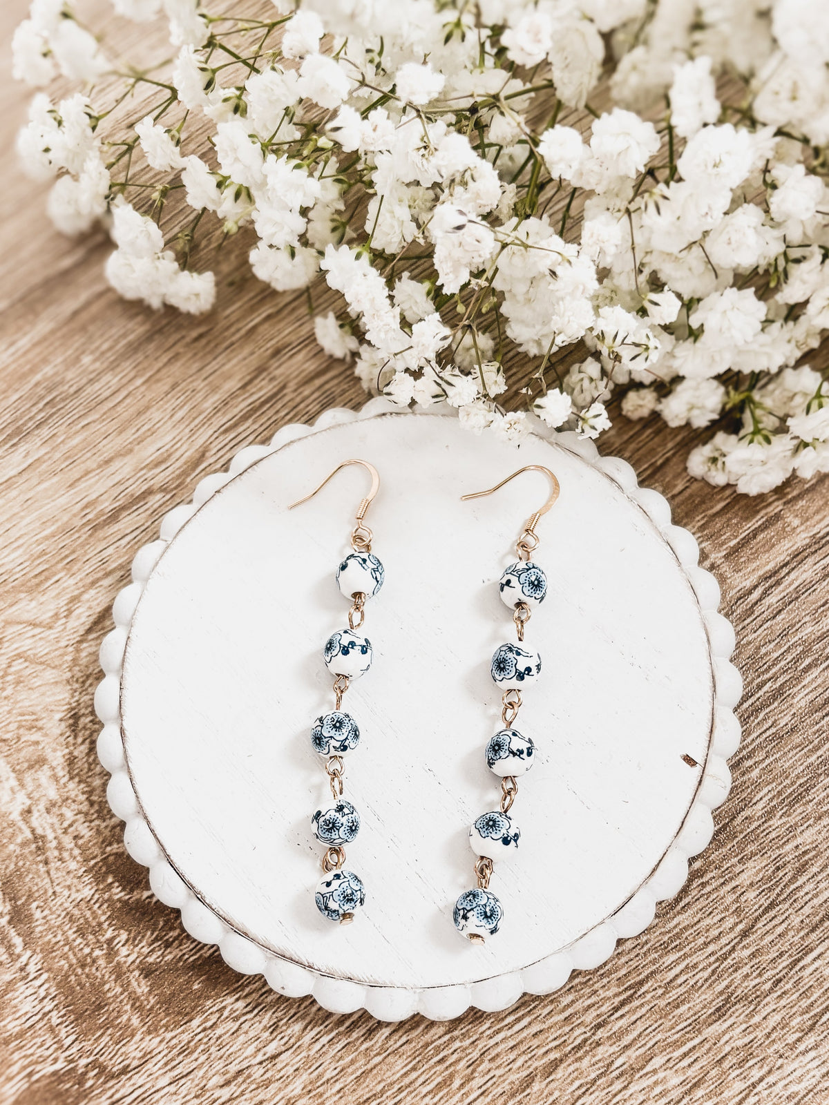 Blue porcelain bead drop earrings on white card; gold-tone hooks, five beads each
