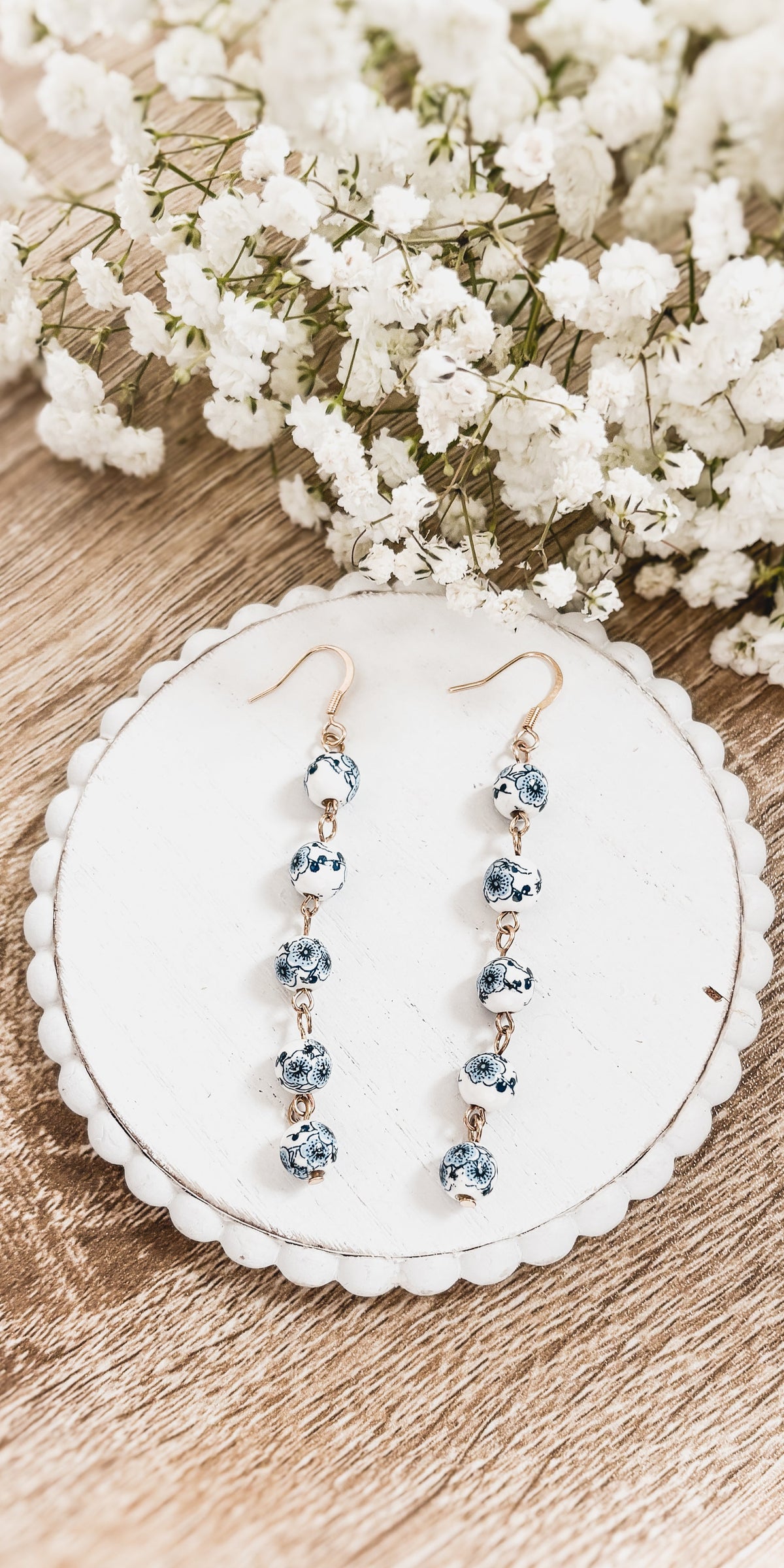 Porcelain drop earrings featuring five blue floral-style round charms on gold hooks