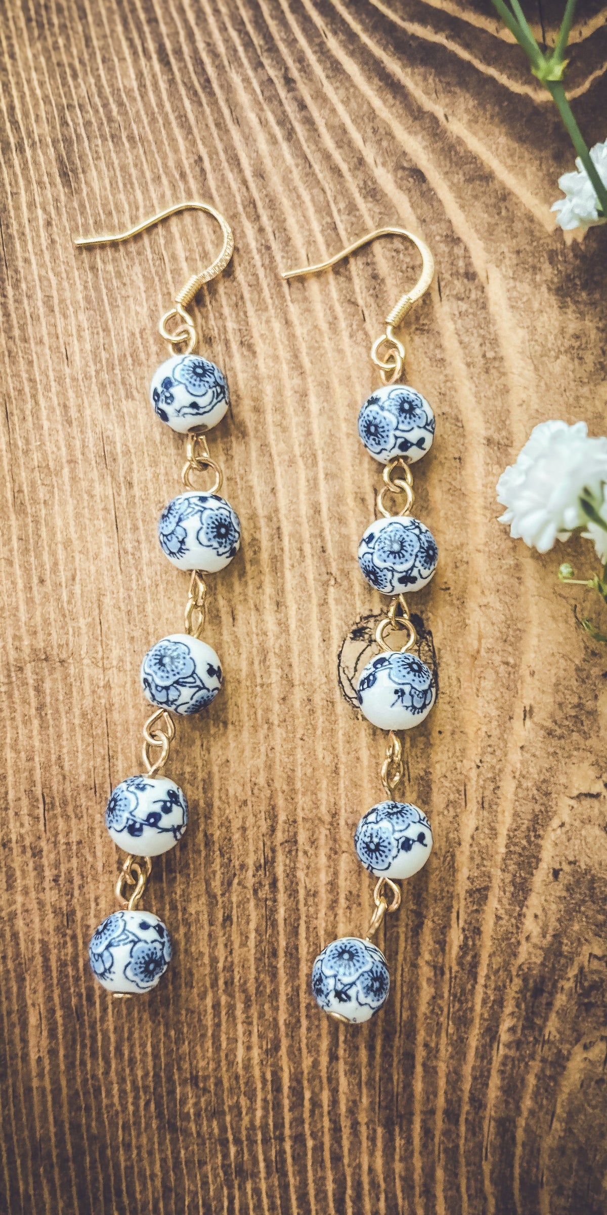 Blue porcelain bead drop earrings with gold-tone hooks, four round beads visible