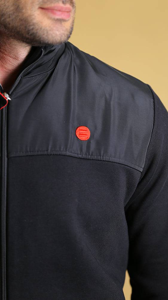 Black tech sweater with zip, red logo patch, and quarter-panel chest seam