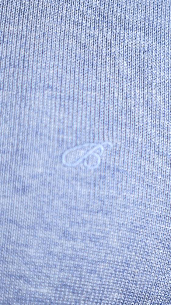Powder blue sweater knit close-up with small emblem detail on chest