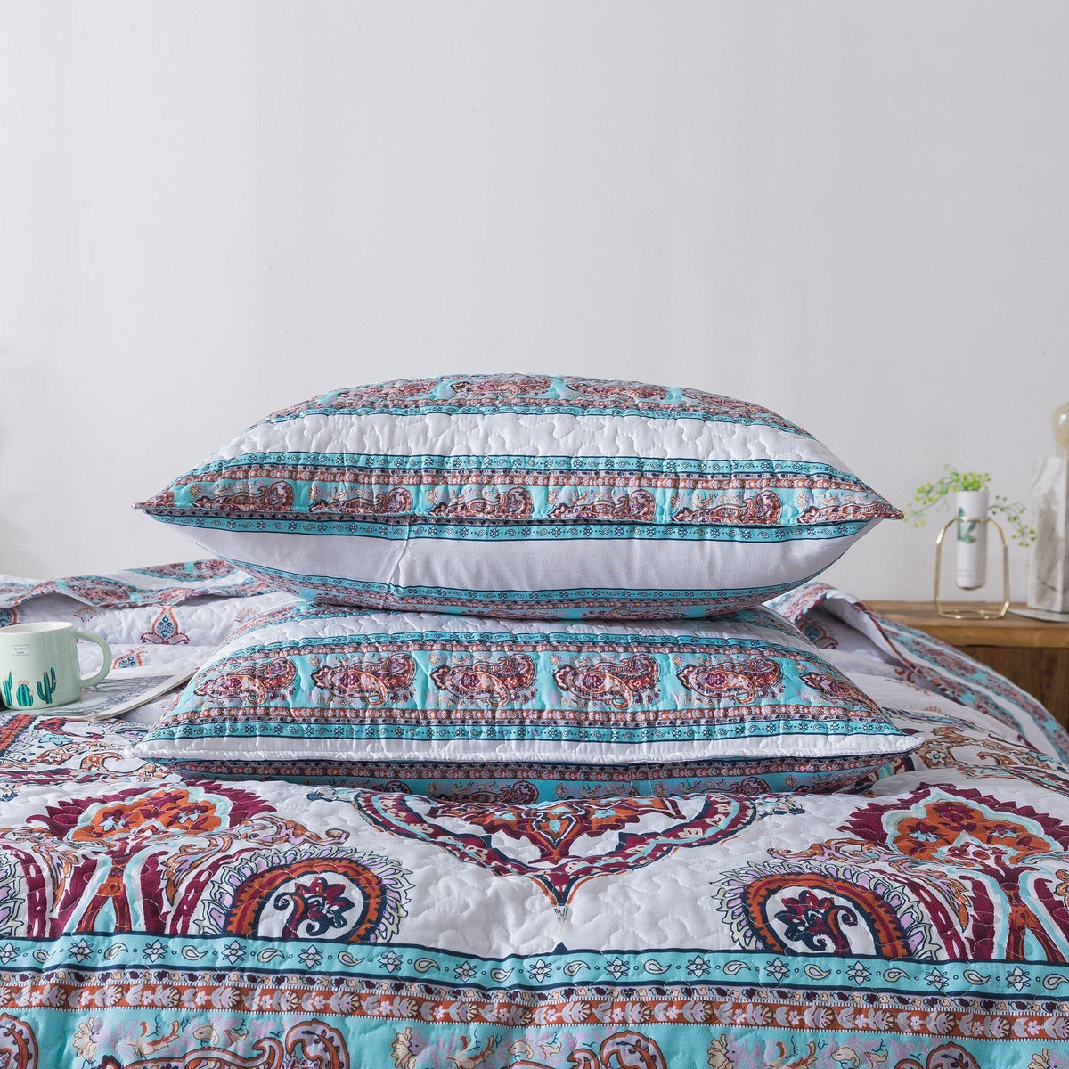 White quilt with blue-striped border and red-blue paisley center motif, with pillow