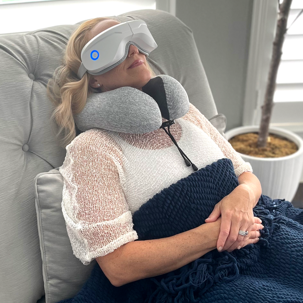 Eye massager with heat: white device and gray neck pillow strap