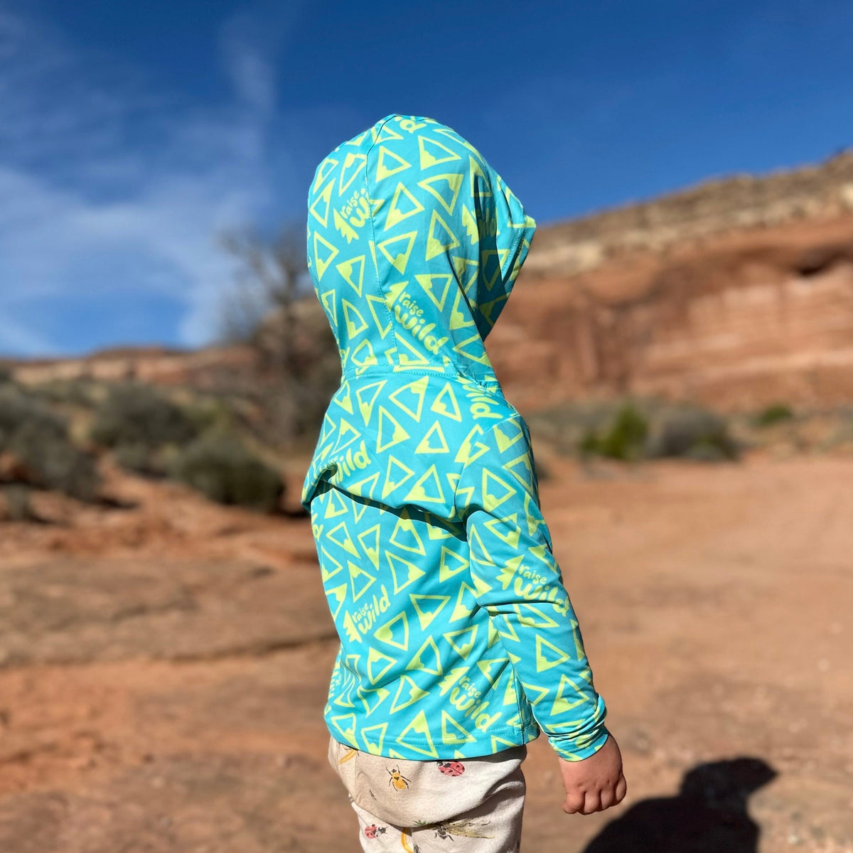 Kids' sun hoodie in teal with yellow geometric triangle pattern, hooded side view