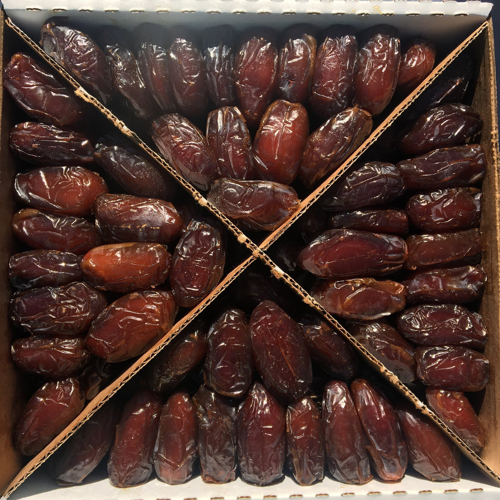 Soft Medjool dates in a cardboard box, tightly packed dark red dates