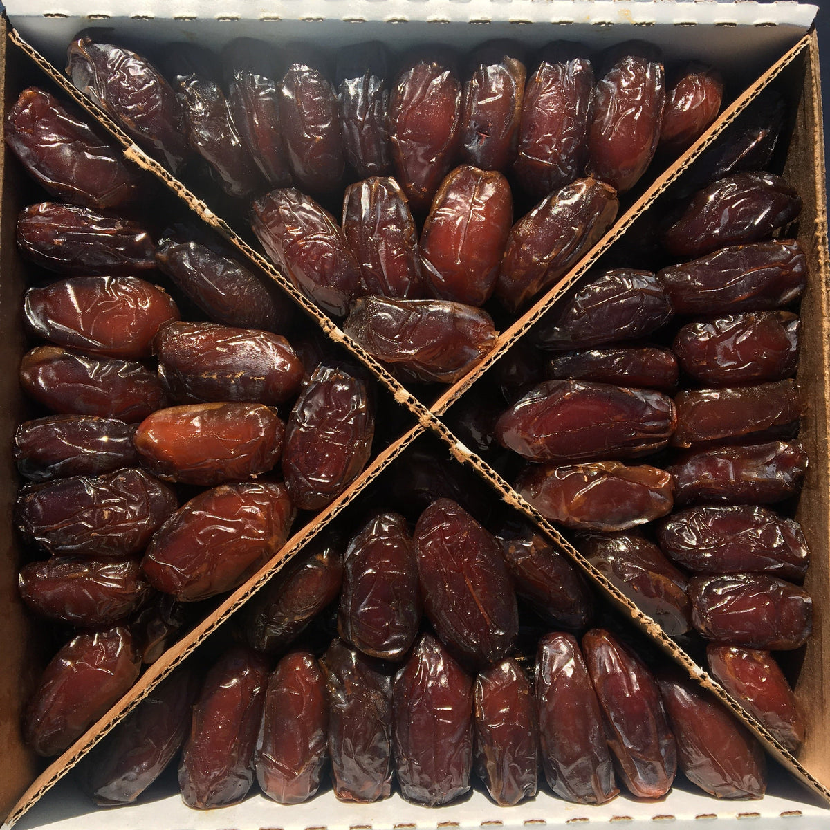 Soft Medjool dates in a cardboard box, tightly packed dark red dates