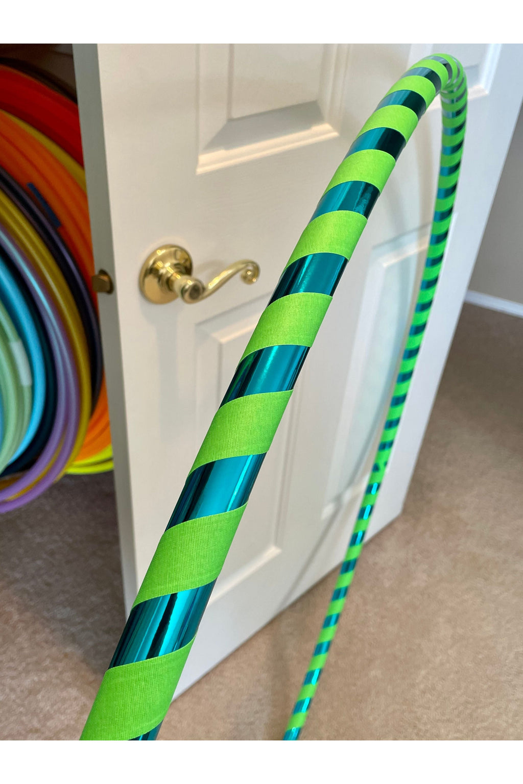 Green and teal striped hula hoop with reflective tape wraps and grip sections