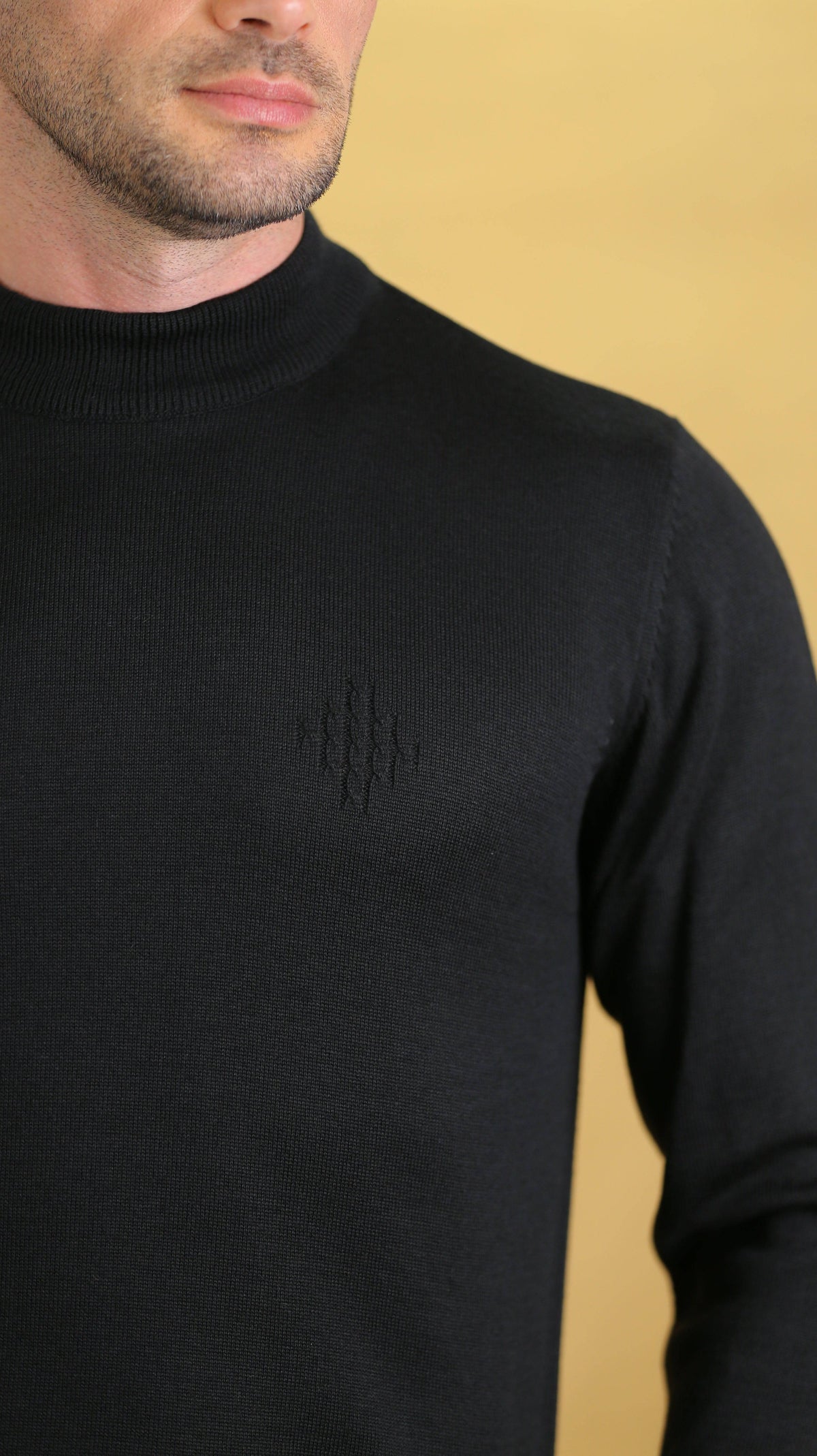 Black crewneck sweater close-up with ribbed collar and smooth knit