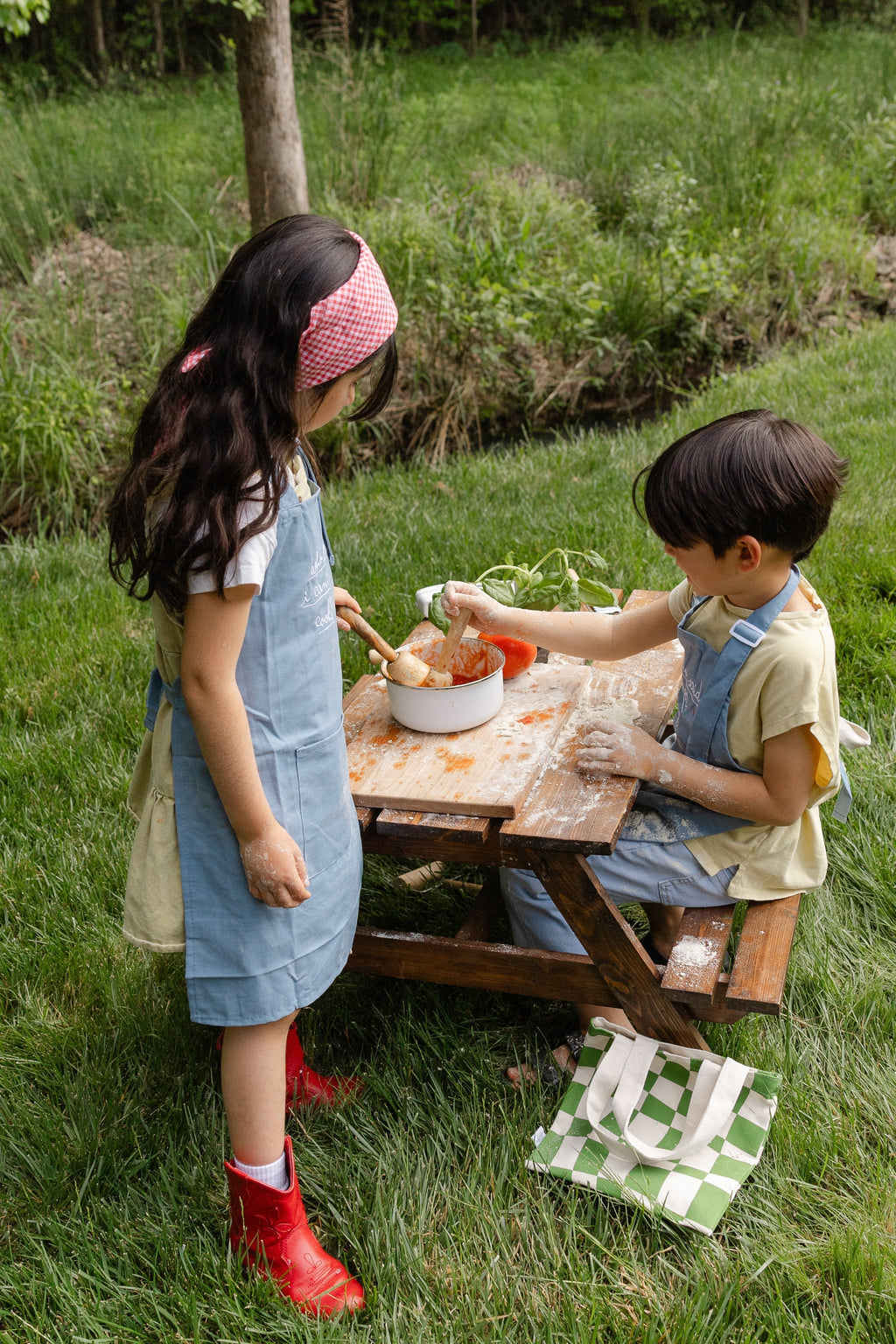 Kids blue chambray linen cooking apron worn outdoors with embroidered script bib front