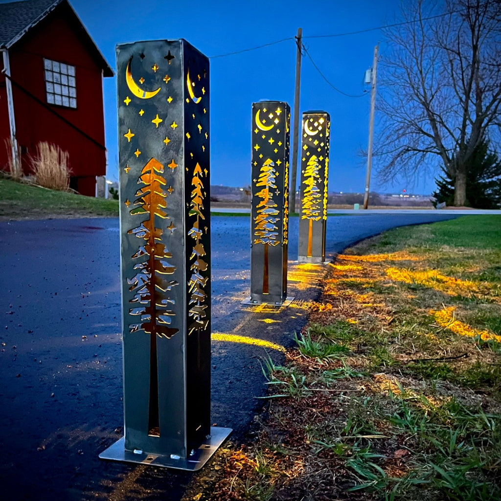 Steel solar light pillar with star, moon, and pine tree cutout lights on all sides.