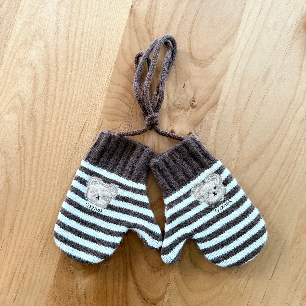 Kids winter mittens with dark gray and white stripes, bear patches, and tie strings