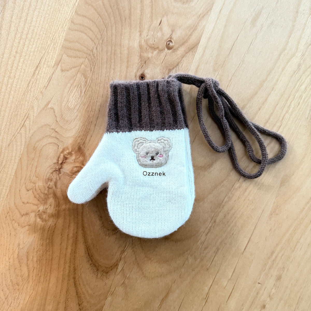 Kids winter mitten with light blue knit, dark ribbed cuff, and bear patch with tie